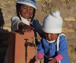 Bolivian girls at village water tap.